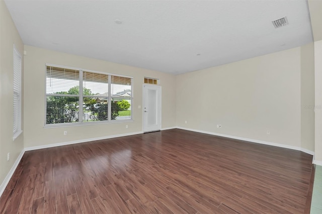 spare room with wood finished floors, visible vents, and baseboards