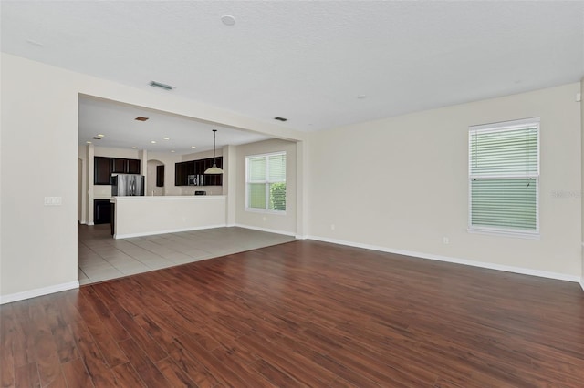 unfurnished living room with dark wood finished floors, baseboards, and visible vents