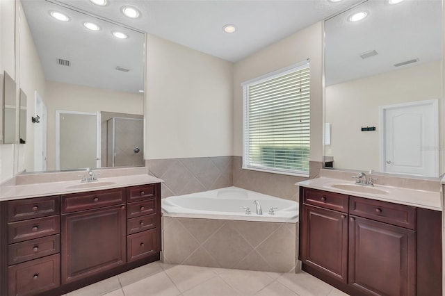 bathroom with tile patterned flooring, a bath, a stall shower, and a sink