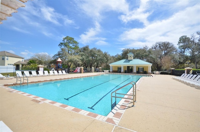 community pool with a patio, fence, playground community, and an outbuilding