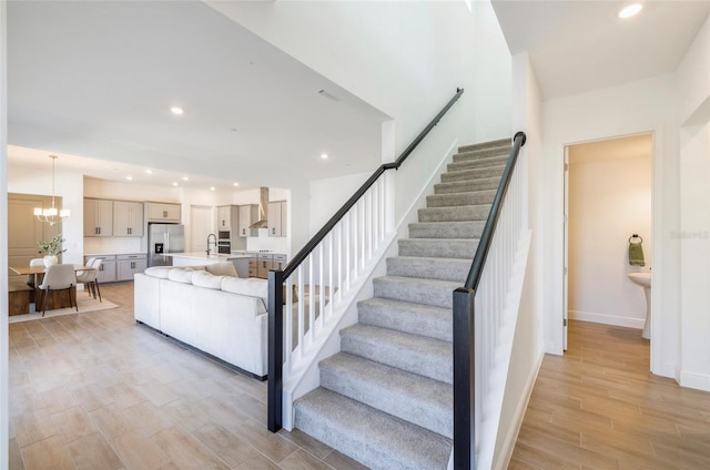 stairway with a notable chandelier, recessed lighting, baseboards, and wood tiled floor