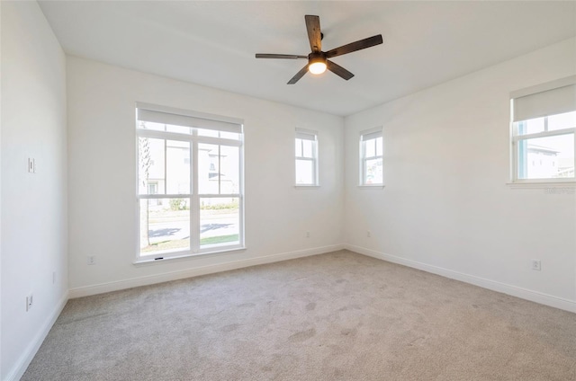 spare room with light colored carpet, baseboards, and ceiling fan