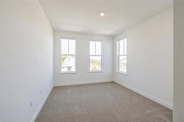 spare room featuring baseboards, light carpet, and a textured ceiling