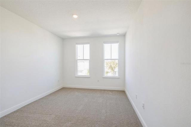 unfurnished room with light colored carpet and baseboards