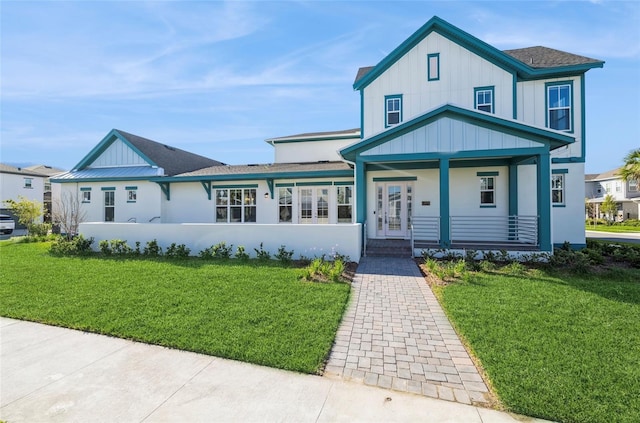 view of front facade featuring board and batten siding, a front yard, and roof with shingles