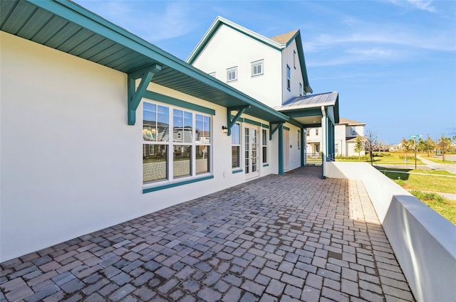 view of home's exterior featuring decorative driveway, metal roof, and stucco siding