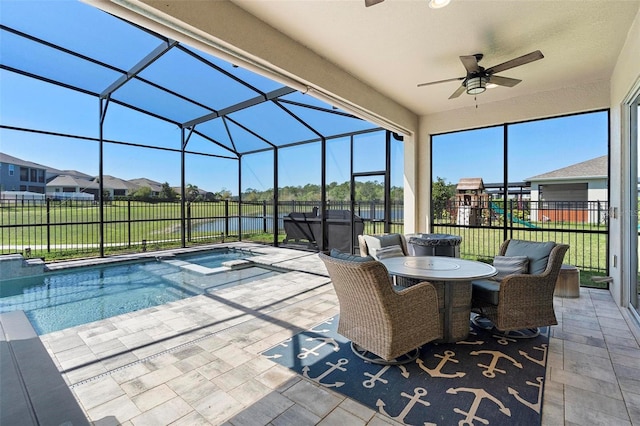 view of pool with glass enclosure, a patio area, fence, and a ceiling fan