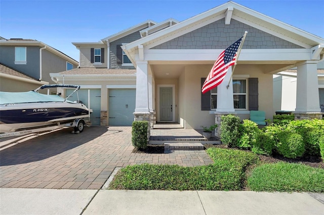 craftsman house featuring decorative driveway, a garage, and stucco siding