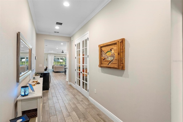 hallway featuring baseboards, visible vents, light wood finished floors, recessed lighting, and crown molding