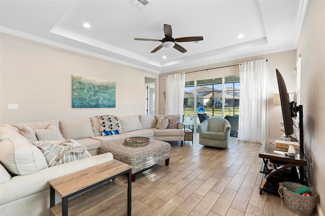 living area featuring a ceiling fan, a raised ceiling, light wood-style floors, and visible vents