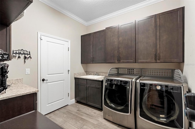 clothes washing area featuring light wood finished floors, washer and clothes dryer, ornamental molding, cabinet space, and a textured ceiling