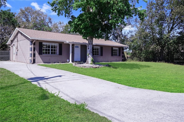 ranch-style house with fence, stucco siding, concrete driveway, a front lawn, and a garage