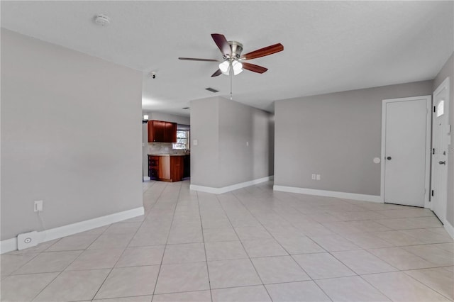 unfurnished living room with light tile patterned floors, visible vents, baseboards, and a ceiling fan