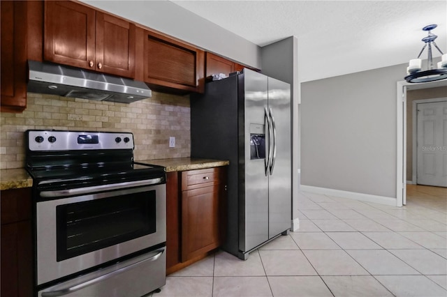 kitchen featuring under cabinet range hood, light stone counters, stainless steel appliances, light tile patterned flooring, and decorative backsplash