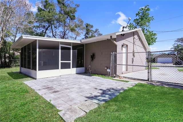 back of property with concrete block siding, a gate, fence, a sunroom, and a lawn