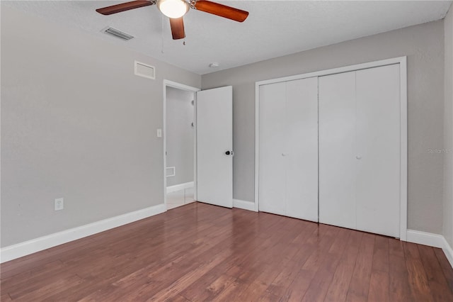 unfurnished bedroom featuring a closet, visible vents, baseboards, and wood finished floors