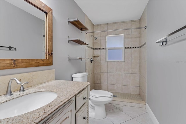 bathroom with a tile shower, tile patterned flooring, toilet, and vanity