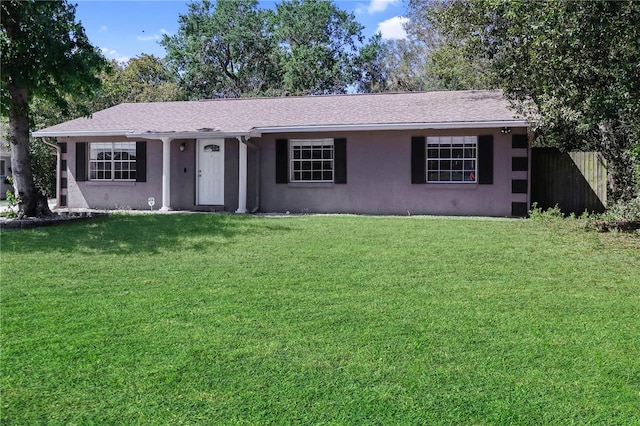 ranch-style home featuring stucco siding, a front lawn, and fence