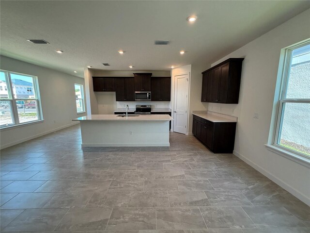 kitchen with visible vents, a sink, appliances with stainless steel finishes, light countertops, and baseboards