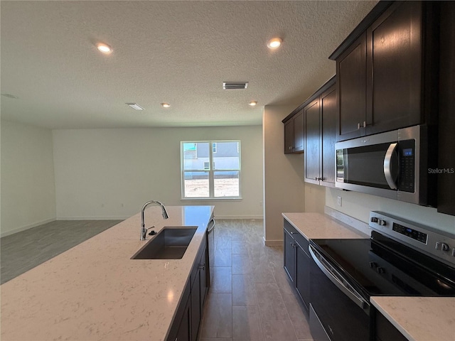 kitchen featuring visible vents, baseboards, light stone countertops, stainless steel appliances, and a sink