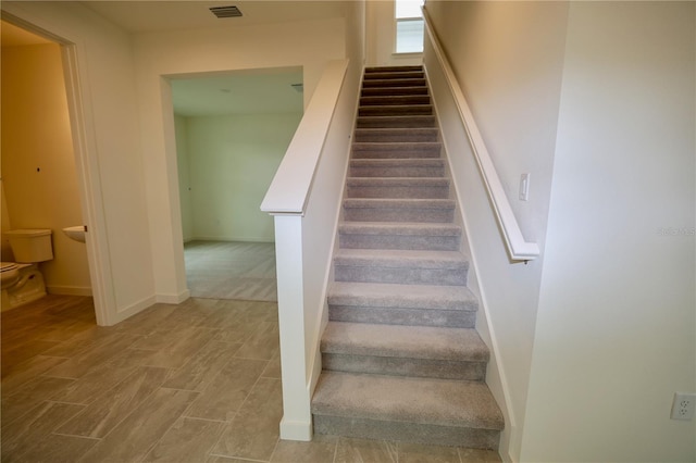 staircase featuring visible vents, baseboards, and wood finished floors