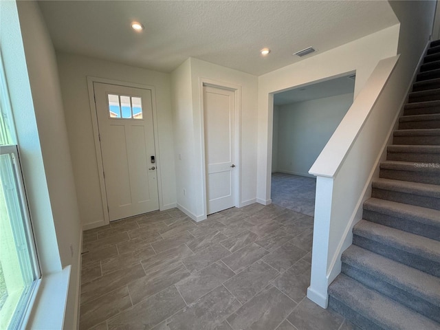 entrance foyer with baseboards, visible vents, recessed lighting, stairs, and a textured ceiling