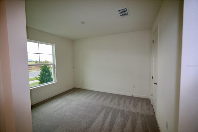 spare room with carpet flooring, baseboards, and visible vents