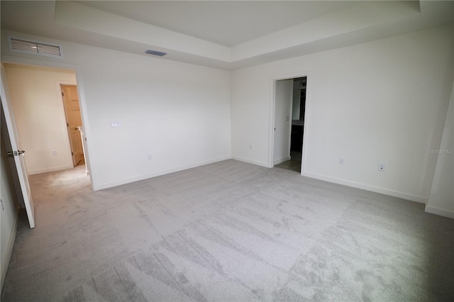 unfurnished room with visible vents, a tray ceiling, and carpet floors