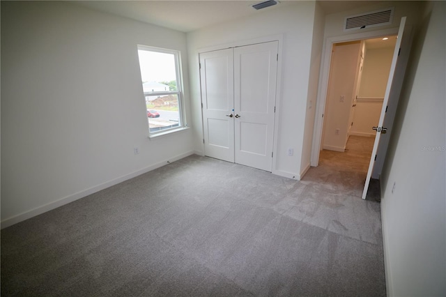 unfurnished bedroom with visible vents, baseboards, light colored carpet, and a closet