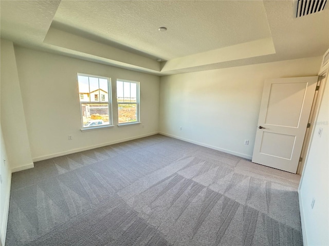 empty room featuring visible vents, a tray ceiling, a textured ceiling, carpet flooring, and baseboards