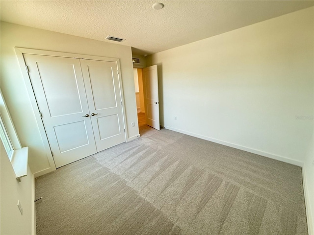 unfurnished bedroom with visible vents, carpet floors, a textured ceiling, and baseboards