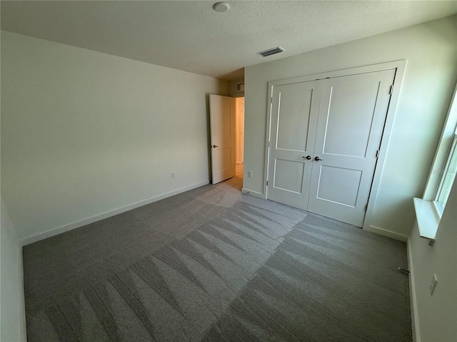 unfurnished bedroom featuring visible vents, baseboards, carpet, a closet, and a textured ceiling