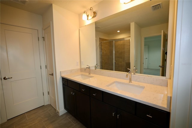 bathroom featuring double vanity, visible vents, a stall shower, and a sink