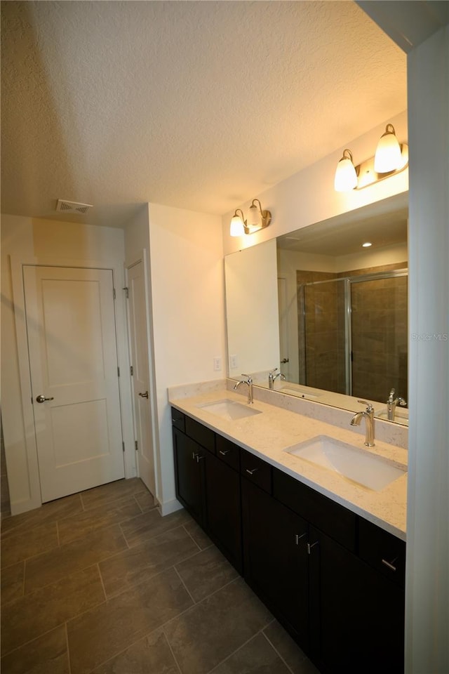 full bath with a sink, visible vents, double vanity, and a shower stall