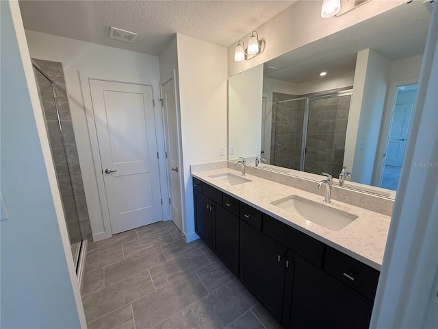 full bathroom featuring double vanity, a shower stall, and a sink