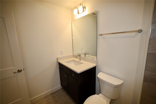 bathroom with toilet, vanity, and baseboards