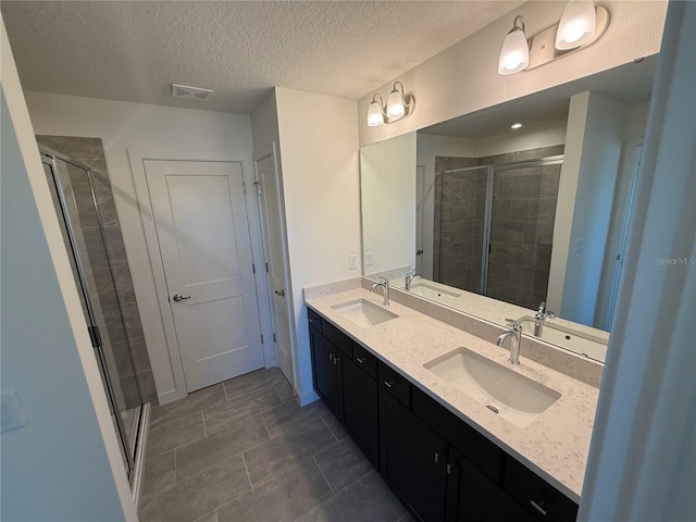 bathroom with a sink, visible vents, and a shower stall