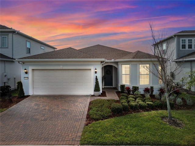 view of front facade with a front yard, decorative driveway, an attached garage, and stucco siding