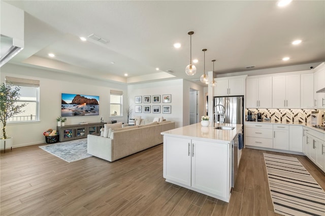 kitchen with visible vents, light wood finished floors, a tray ceiling, appliances with stainless steel finishes, and open floor plan