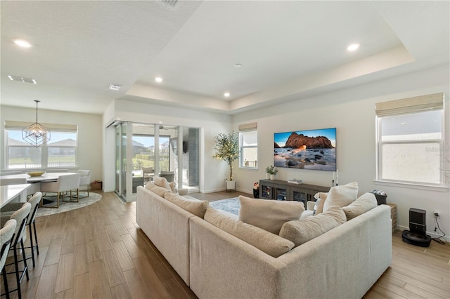 living room with a raised ceiling, baseboards, and wood finished floors