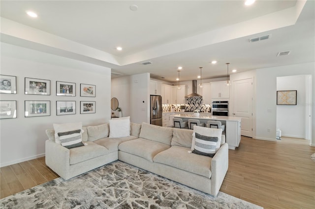 living area featuring recessed lighting, visible vents, baseboards, and light wood-style flooring