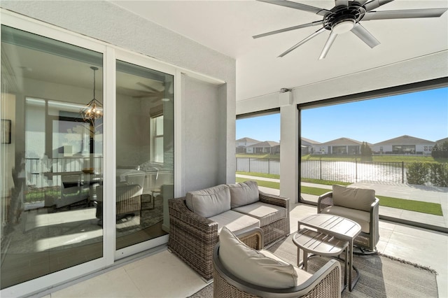 sunroom / solarium featuring plenty of natural light, ceiling fan with notable chandelier, and a water view