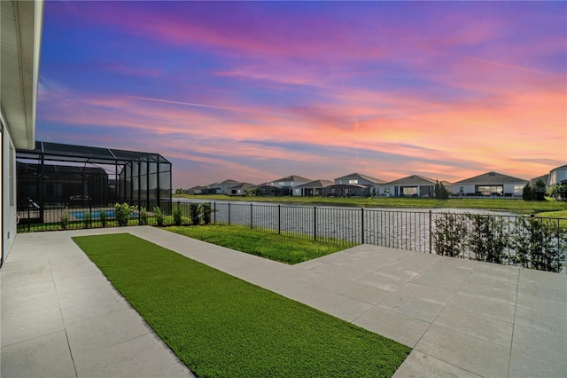 view of yard featuring a water view, a residential view, glass enclosure, a fenced backyard, and a patio