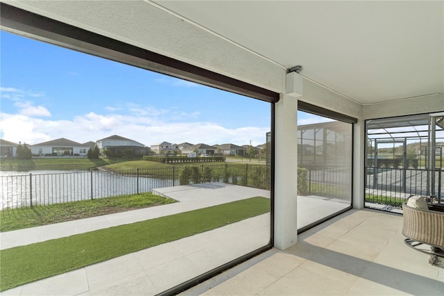 unfurnished sunroom featuring a residential view and a water view