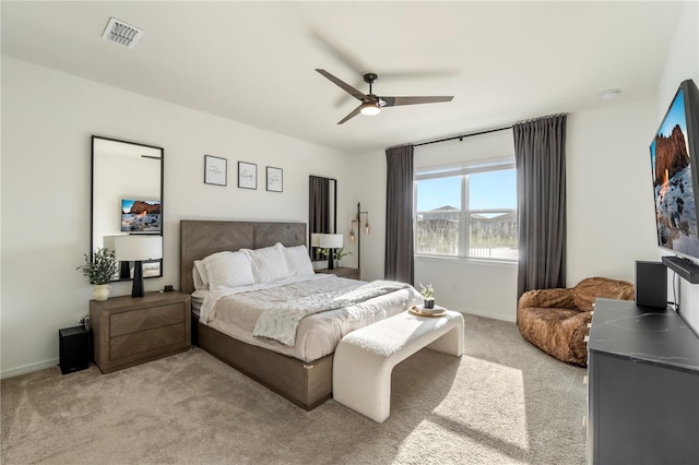 bedroom featuring visible vents, light colored carpet, baseboards, and ceiling fan