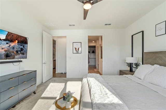 carpeted bedroom with connected bathroom, visible vents, and ceiling fan