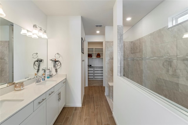 full bath featuring wood finish floors, visible vents, a walk in closet, a sink, and walk in shower