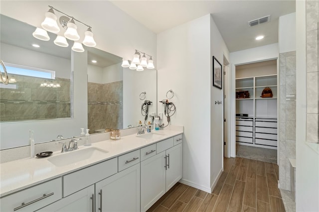 bathroom with a spacious closet, visible vents, wood tiled floor, and a sink