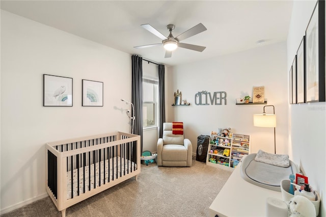 bedroom with a crib, carpet, and ceiling fan