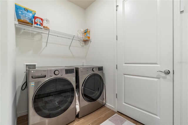 clothes washing area with washing machine and clothes dryer, laundry area, light wood-type flooring, and baseboards